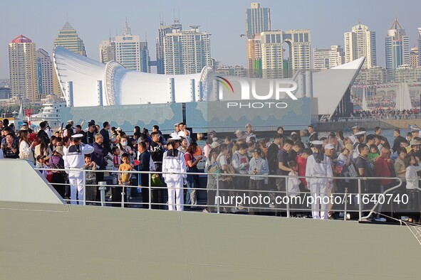 Tourists visit a warship at the port of the International Sailing Center in Qingdao, China, on October 3, 2024. 