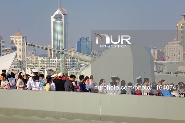 Tourists visit a warship at the port of the International Sailing Center in Qingdao, China, on October 3, 2024. 