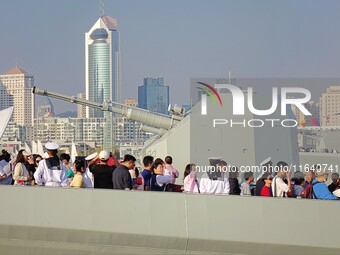 Tourists visit a warship at the port of the International Sailing Center in Qingdao, China, on October 3, 2024. (