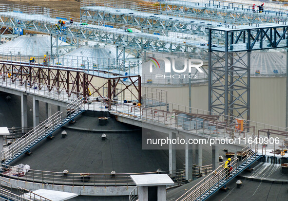 Workers work at the construction site of the first phase of the Hualian grain storage and logistics project at Huangma Port in Huaian City,...