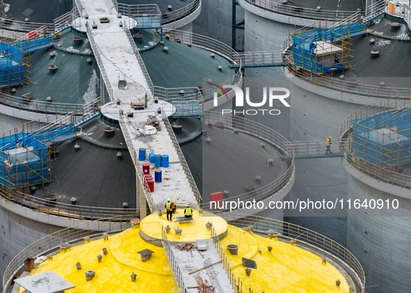 Workers work at the construction site of the first phase of the Hualian grain storage and logistics project at Huangma Port in Huaian City,...