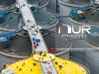 Workers work at the construction site of the first phase of the Hualian grain storage and logistics project at Huangma Port in Huaian City,...