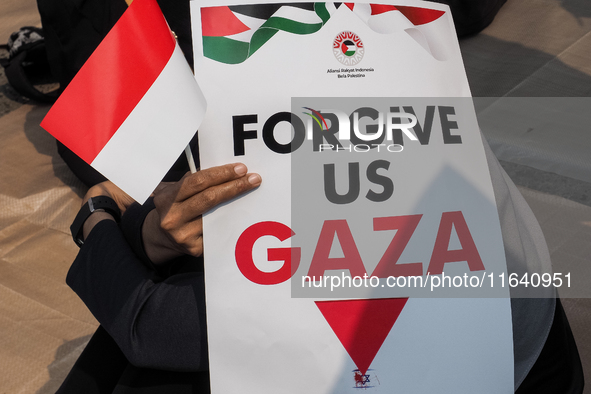 A pro-Palestinian demonstrator holds a poster that reads 'FORGIVE US GAZA' during a protest marking the one-year anniversary of the Israel-H...