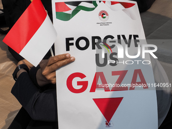 A pro-Palestinian demonstrator holds a poster that reads 'FORGIVE US GAZA' during a protest marking the one-year anniversary of the Israel-H...