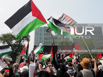 Pro-Palestinian demonstrators carry Palestinian flags during a protest marking the one-year anniversary of the Israel-Hamas conflict in fron...