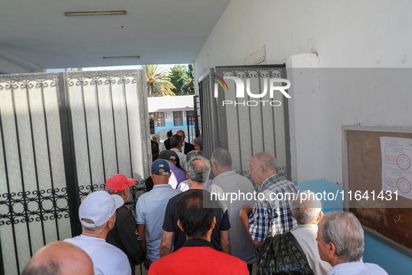 Tunisian voters enter the polling station at the official opening time to cast their votes during the presidential election in Ariana, a sub...