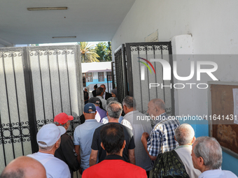 Tunisian voters enter the polling station at the official opening time to cast their votes during the presidential election in Ariana, a sub...