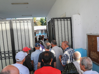 Tunisian voters enter the polling station at the official opening time to cast their votes during the presidential election in Ariana, a sub...