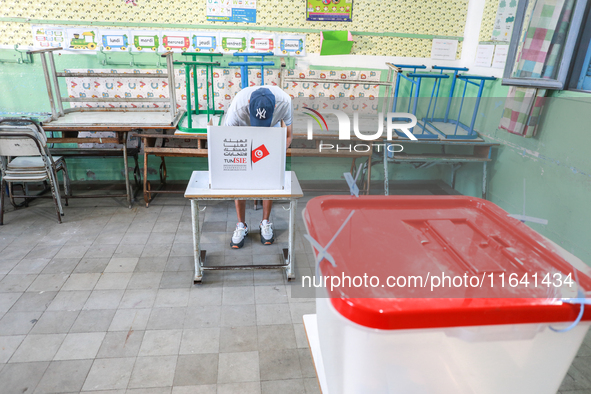 A Tunisian man fills his ballot paper at a polling station during the presidential election in Ariana, a suburb of Tunis, Tunisia, on Octobe...