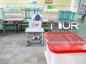 A Tunisian man fills his ballot paper at a polling station during the presidential election in Ariana, a suburb of Tunis, Tunisia, on Octobe...