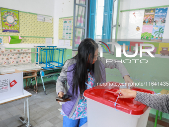 A Tunisian young woman casts her ballot at a polling station during the presidential election in Ariana, a suburb of Tunis, Tunisia, on Octo...