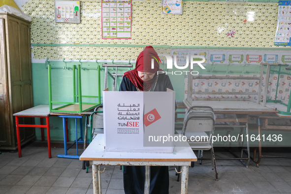 A Tunisian woman fills her ballot paper at a polling station during the presidential election in Ariana, a suburb of Tunis, Tunisia, on Octo...