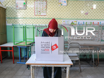 A Tunisian woman fills her ballot paper at a polling station during the presidential election in Ariana, a suburb of Tunis, Tunisia, on Octo...