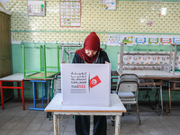 A Tunisian woman fills her ballot paper at a polling station during the presidential election in Ariana, a suburb of Tunis, Tunisia, on Octo...