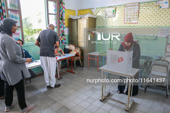 A Tunisian woman fills her ballot paper at a polling station during the presidential election in Ariana, a suburb of Tunis, Tunisia, on Octo...