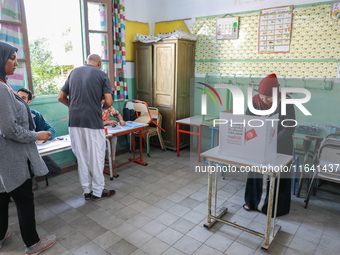 A Tunisian woman fills her ballot paper at a polling station during the presidential election in Ariana, a suburb of Tunis, Tunisia, on Octo...