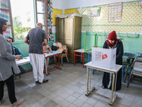 A Tunisian woman fills her ballot paper at a polling station during the presidential election in Ariana, a suburb of Tunis, Tunisia, on Octo...