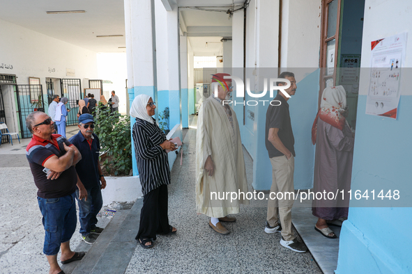 Tunisians line up at a polling station as they await their turn to cast their vote during the presidential election in Ariana, a suburb of T...