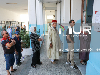 Tunisians line up at a polling station as they await their turn to cast their vote during the presidential election in Ariana, a suburb of T...