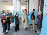 Tunisians line up at a polling station as they await their turn to cast their vote during the presidential election in Ariana, a suburb of T...