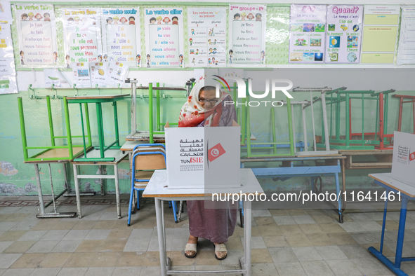 A Tunisian elderly woman fills her ballot paper at a polling station during the presidential election in Ariana, a suburb of Tunis, Tunisia,...