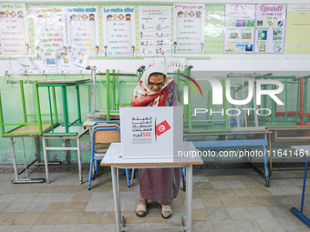 A Tunisian elderly woman fills her ballot paper at a polling station during the presidential election in Ariana, a suburb of Tunis, Tunisia,...