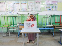 A Tunisian elderly woman fills her ballot paper at a polling station during the presidential election in Ariana, a suburb of Tunis, Tunisia,...