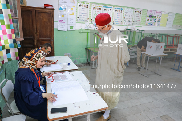 A Tunisian elderly man prepares to cast his vote at a polling station during the presidential election in Ariana, a suburb of Tunis, Tunisia...