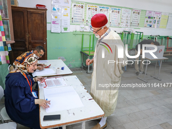 A Tunisian elderly man prepares to cast his vote at a polling station during the presidential election in Ariana, a suburb of Tunis, Tunisia...