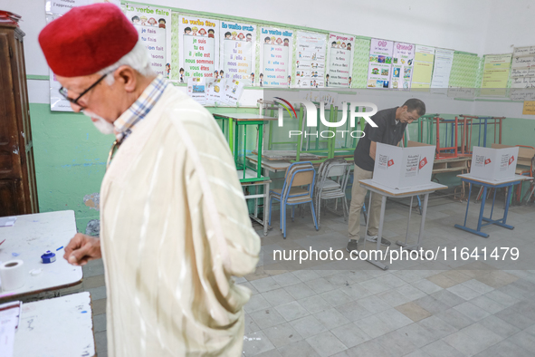 A Tunisian man fills his ballot paper at a polling station during the presidential election in Ariana, a suburb of Tunis, Tunisia, on Octobe...