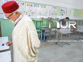 A Tunisian man fills his ballot paper at a polling station during the presidential election in Ariana, a suburb of Tunis, Tunisia, on Octobe...