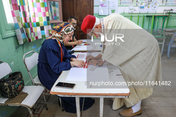 A Tunisian elderly man prepares to cast his vote at a polling station during the presidential election in Ariana, a suburb of Tunis, Tunisia...