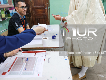 A Tunisian elderly man has his finger inked as he prepares to cast his vote at a polling station during the presidential election in Ariana,...