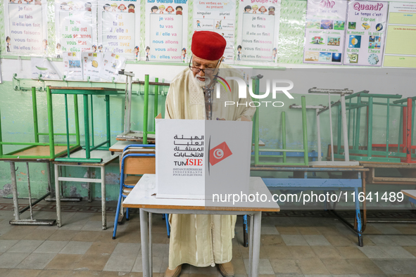 A Tunisian elderly man fills his ballot paper at a polling station during the presidential election in Ariana, a suburb of Tunis, Tunisia, o...