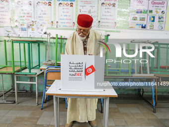 A Tunisian elderly man fills his ballot paper at a polling station during the presidential election in Ariana, a suburb of Tunis, Tunisia, o...