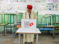 A Tunisian elderly man fills his ballot paper at a polling station during the presidential election in Ariana, a suburb of Tunis, Tunisia, o...