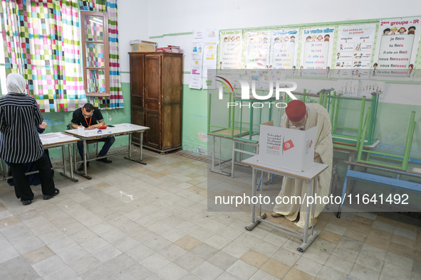 A Tunisian elderly man fills his ballot paper at a polling station during the presidential election in Ariana, a suburb of Tunis, Tunisia, o...