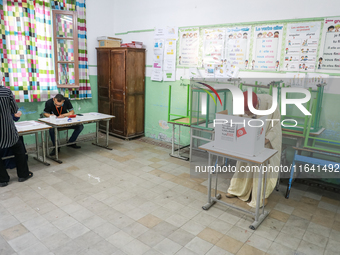 A Tunisian elderly man fills his ballot paper at a polling station during the presidential election in Ariana, a suburb of Tunis, Tunisia, o...