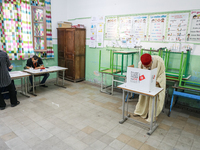 A Tunisian elderly man fills his ballot paper at a polling station during the presidential election in Ariana, a suburb of Tunis, Tunisia, o...