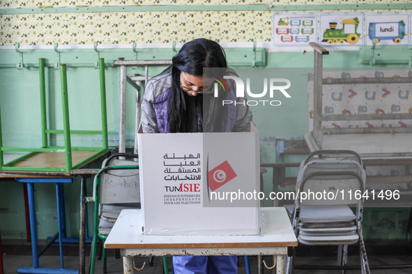 A Tunisian woman fills her ballot paper at a polling station during the presidential election in Ariana, a suburb of Tunis, Tunisia, on Octo...