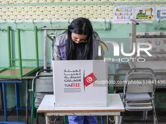 A Tunisian woman fills her ballot paper at a polling station during the presidential election in Ariana, a suburb of Tunis, Tunisia, on Octo...