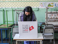 A Tunisian woman fills her ballot paper at a polling station during the presidential election in Ariana, a suburb of Tunis, Tunisia, on Octo...