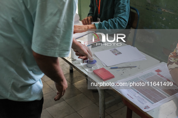 A Tunisian man inks his finger as he prepares to cast his vote at a polling station during the presidential election in Ariana, a suburb of...