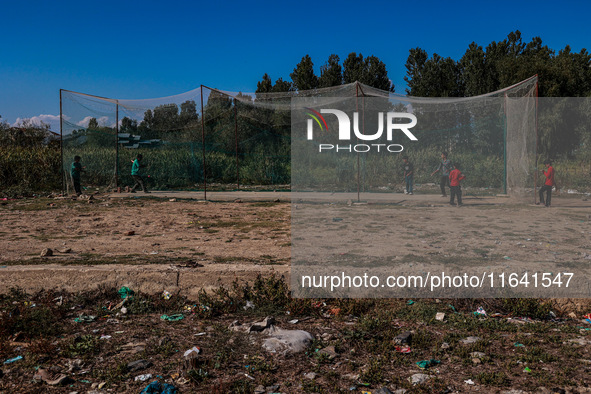 Kashmiri boys play cricket inside a net installed on a roadside in Sopore, Jammu and Kashmir, India, on October 6, 2024 