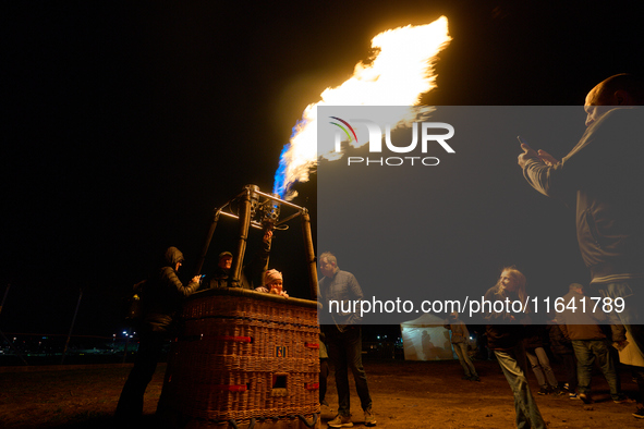 People have their photo taken while flames emit from the bruner of a hot air balloon system at the Warsaw Institute of Aviation in Warsaw, P...