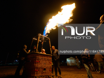 People have their photo taken while flames emit from the bruner of a hot air balloon system at the Warsaw Institute of Aviation in Warsaw, P...