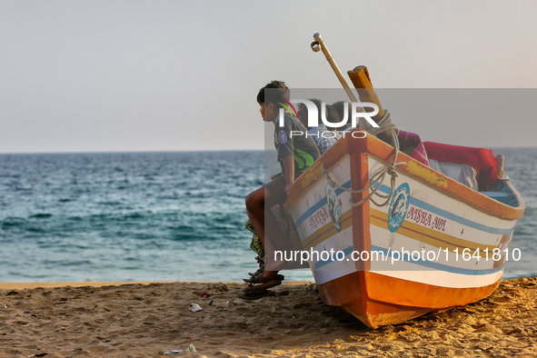 People sit in a fishing boat along Paruthiyoor Beach in Paruthiyoor, Kerala, India, on April 15, 2024. 