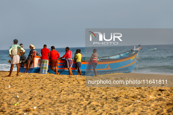 Fishermen rest by a fishing boat by the ocean along Paruthiyoor Beach in Paruthiyoor, Kerala, India, on April 15, 2024. 