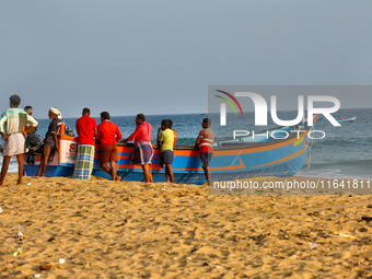 Fishermen rest by a fishing boat by the ocean along Paruthiyoor Beach in Paruthiyoor, Kerala, India, on April 15, 2024. (