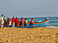 Fishermen rest by a fishing boat by the ocean along Paruthiyoor Beach in Paruthiyoor, Kerala, India, on April 15, 2024. (